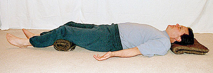 Man lying down with pillows underneath head and knees
